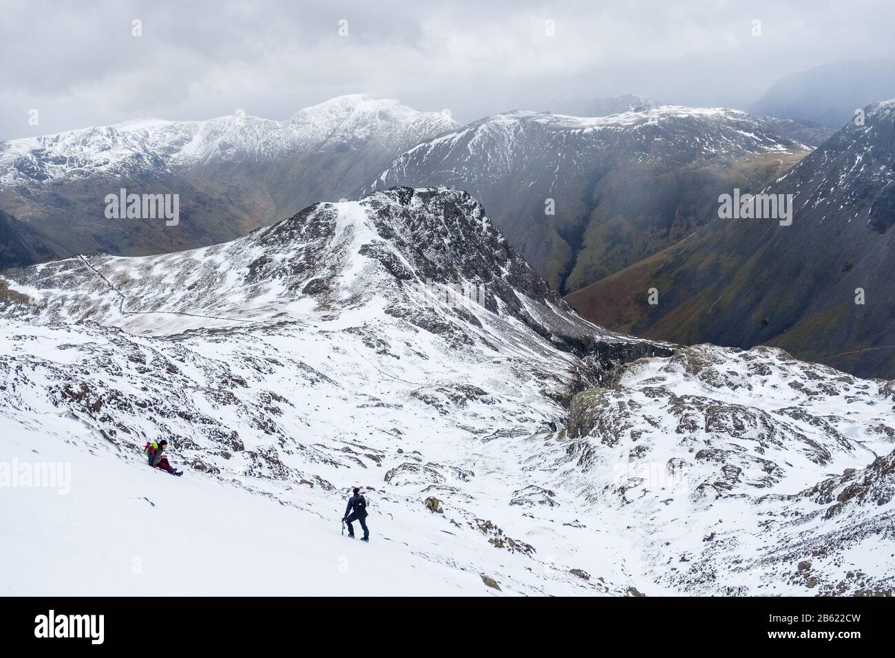 Lingmell, part of the Scafell group of hills, in winter. Lake District National Park, Cumbria, UK. 2 hill walkers in foreground Stock Photo