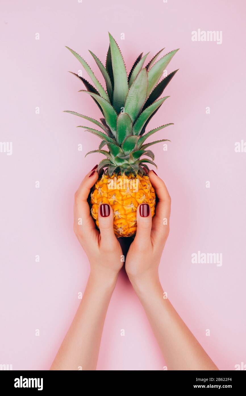 Hands with pineapple on stylish pink background. Stock Photo