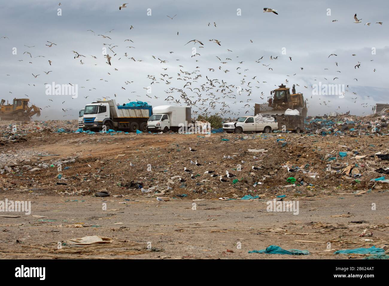 Rubbish piled on a landfill full of trash with vehicles working Stock Photo