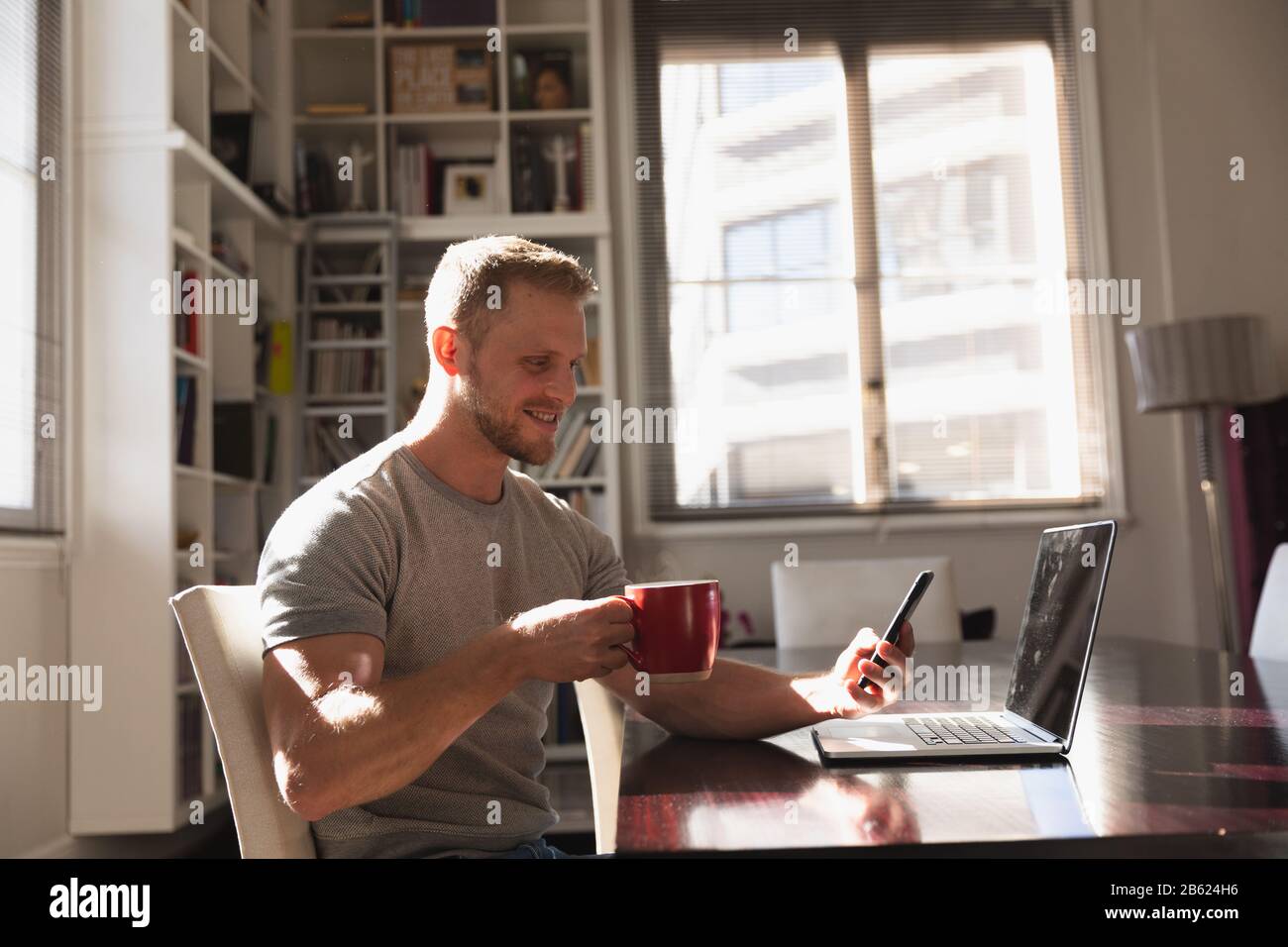 Side view man with coffee using smartphone and laptop Stock Photo