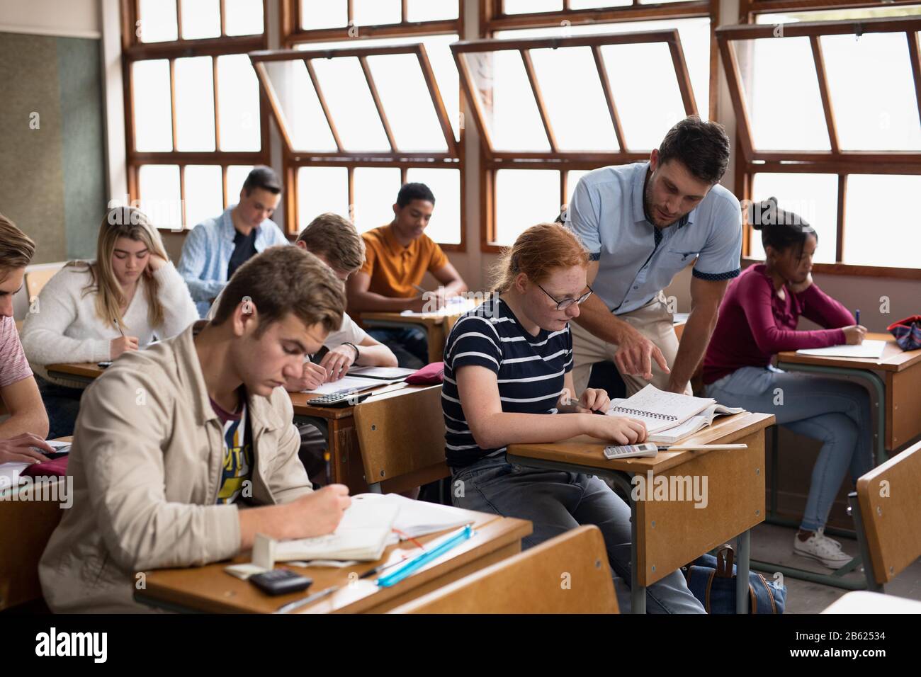 Side view of teacher helping students in class Stock Photo - Alamy