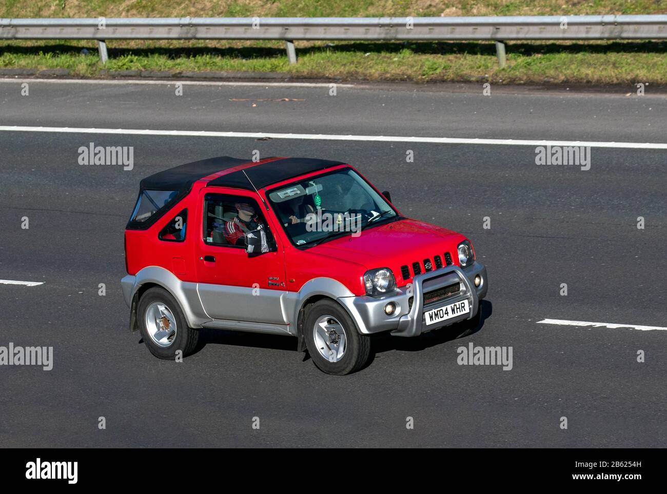 2004 red Suzuki Jimny 02; Vehicular traffic, transport, modern vehicles, saloon cars, vehicle on UK roads, motors, motoring on the M6 motorway Stock Photo