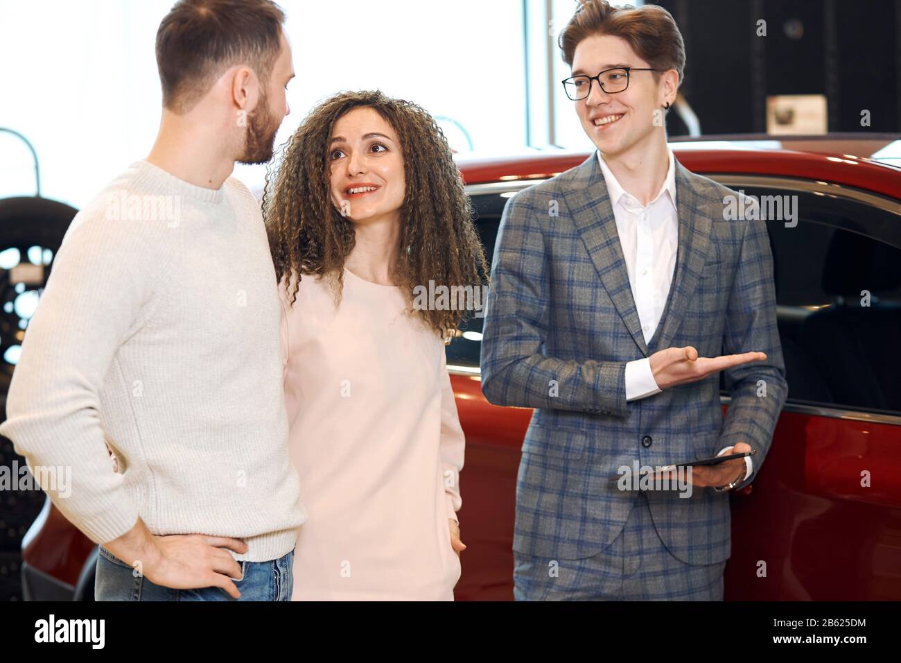 handsome friendly shop assistant showing vehicle to a man and a woman. close up photo. presentation of new models, close up photo Stock Photo