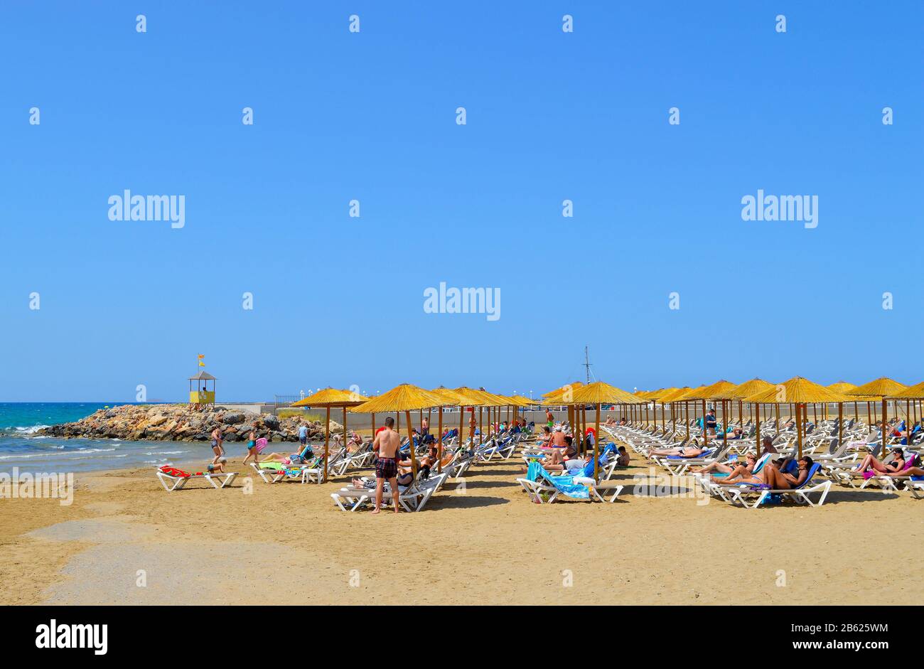 Tourists sunbathing under parasols on Gouves beach in Crete the largest ...