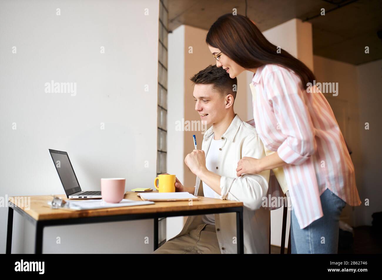 young couple using laptop at home, watching webinar,workshop, close up side view photo. family styding, training seminar. side view photo Stock Photo