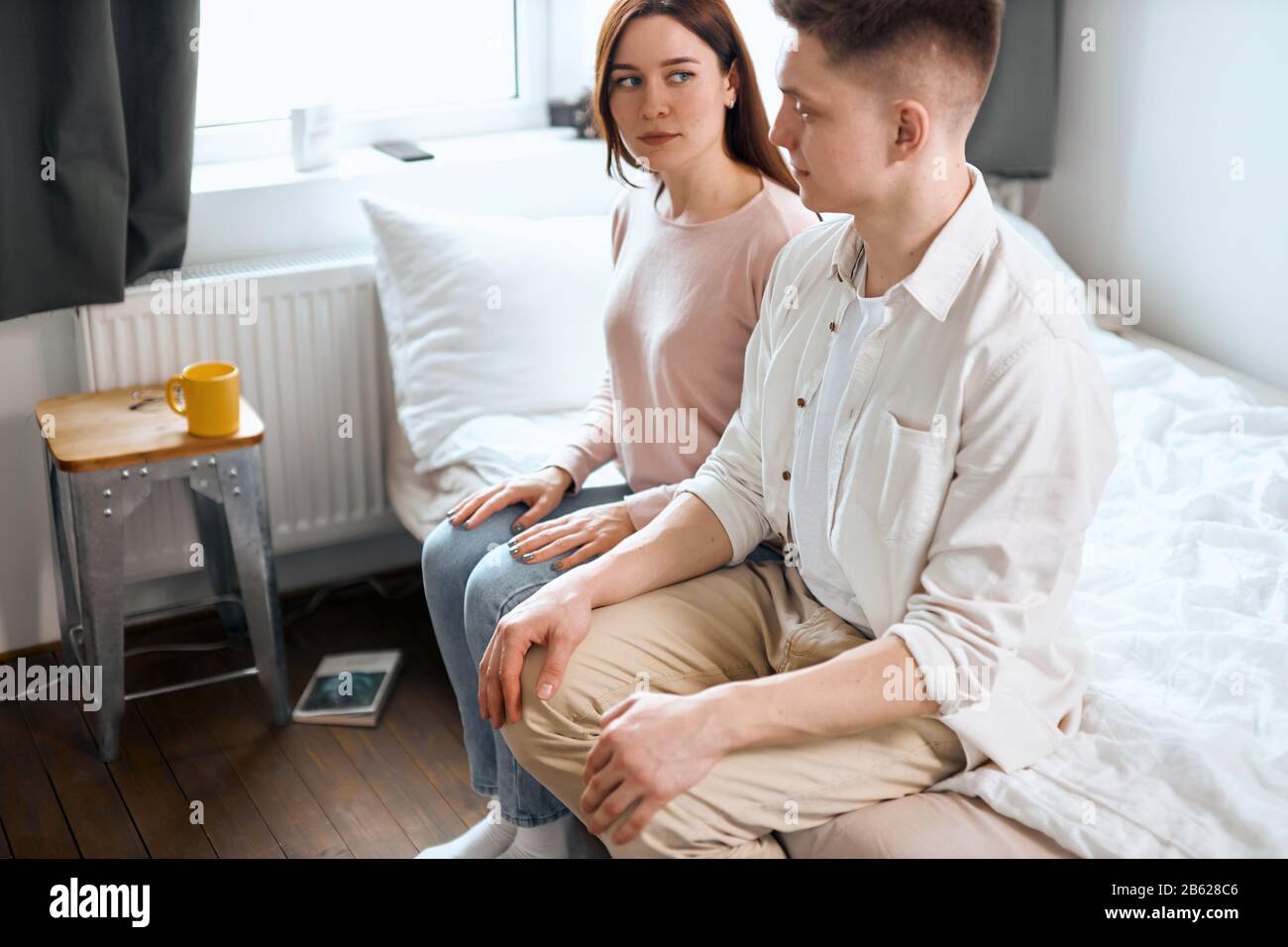 Despaired married couple sitting on the edge of the bed, misunderstaning between couple. close up side view photo.offensive couple looking at each oth Stock Photo