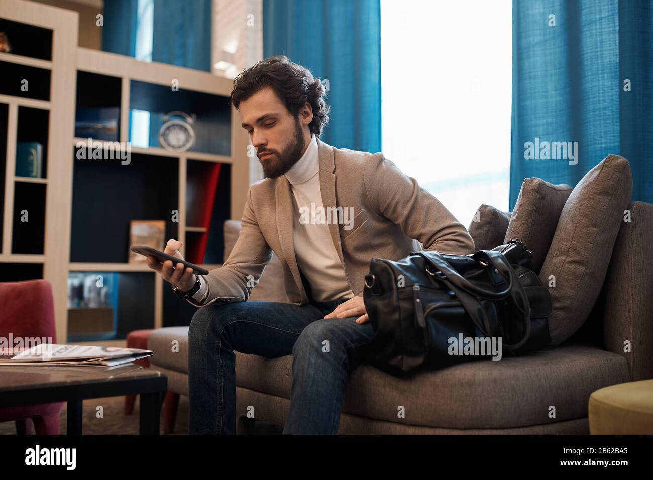 clever man in fashion jacket having a rest on the sofe, texting message, chatting online with friends, clients , business, lifestyle, free time, spare Stock Photo