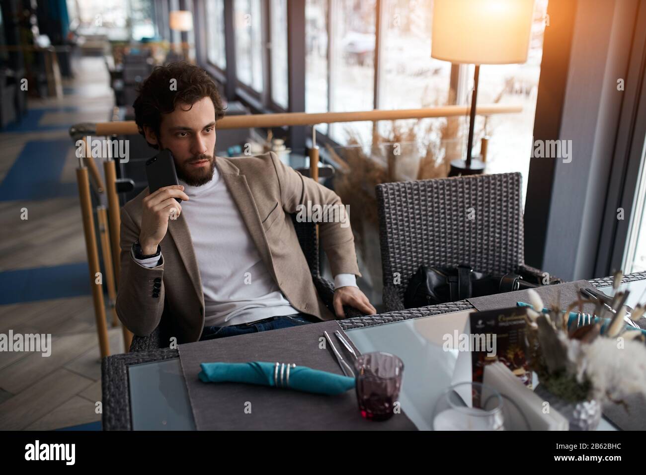 Young serious man making a phone call in coffee shop, sitting at the table, solving business problem. close up photo Stock Photo
