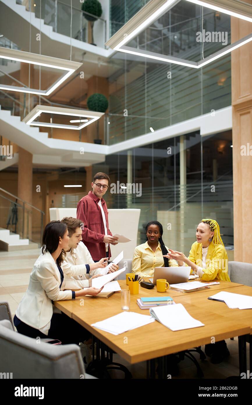 young people discussing a bigtime deal, checking bills, young business people closuring of a deal. woman pointing to the document, showing mistakes in Stock Photo