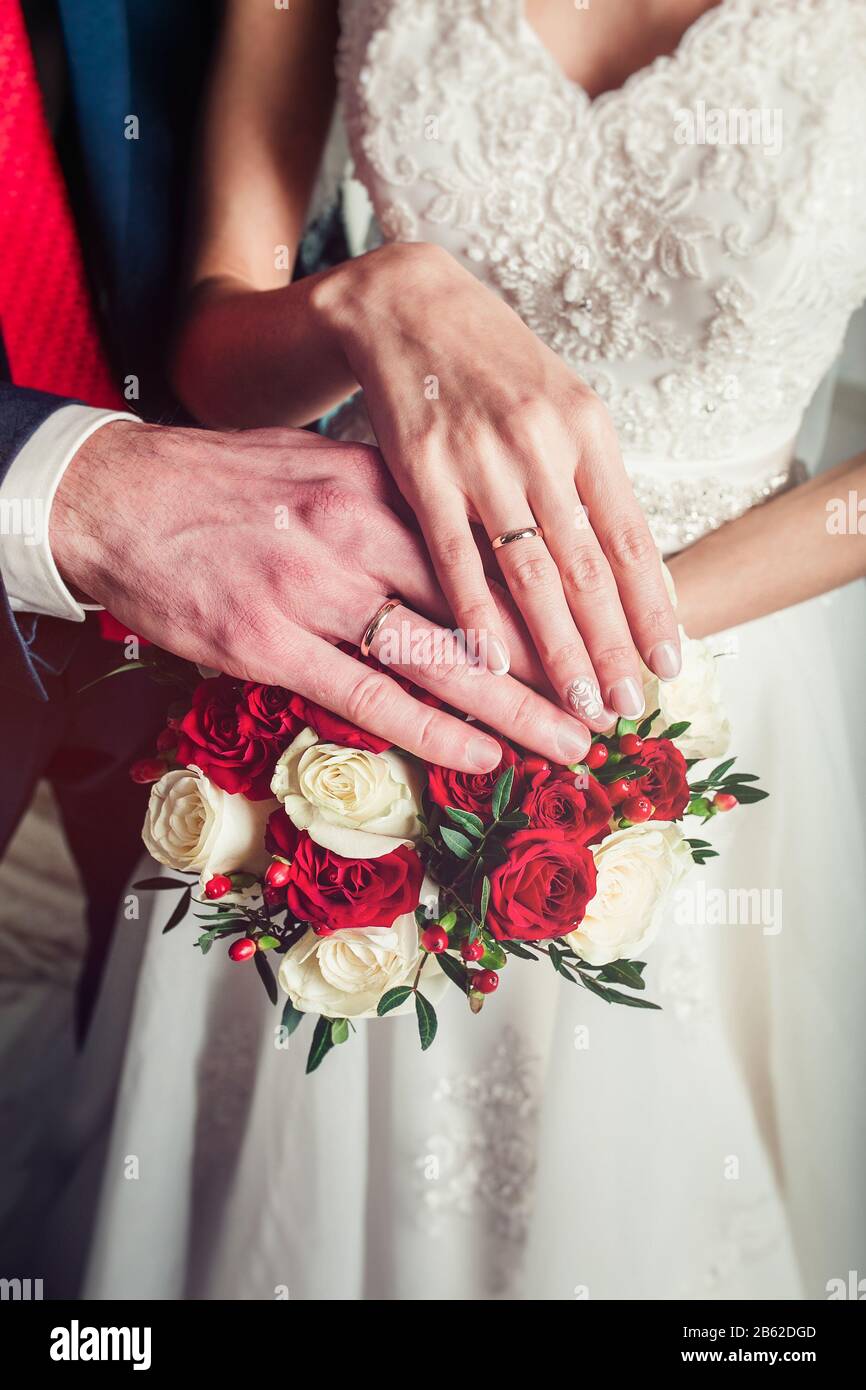 Hands bride and groom with rings on the bouquet closeup Stock Photo - Alamy