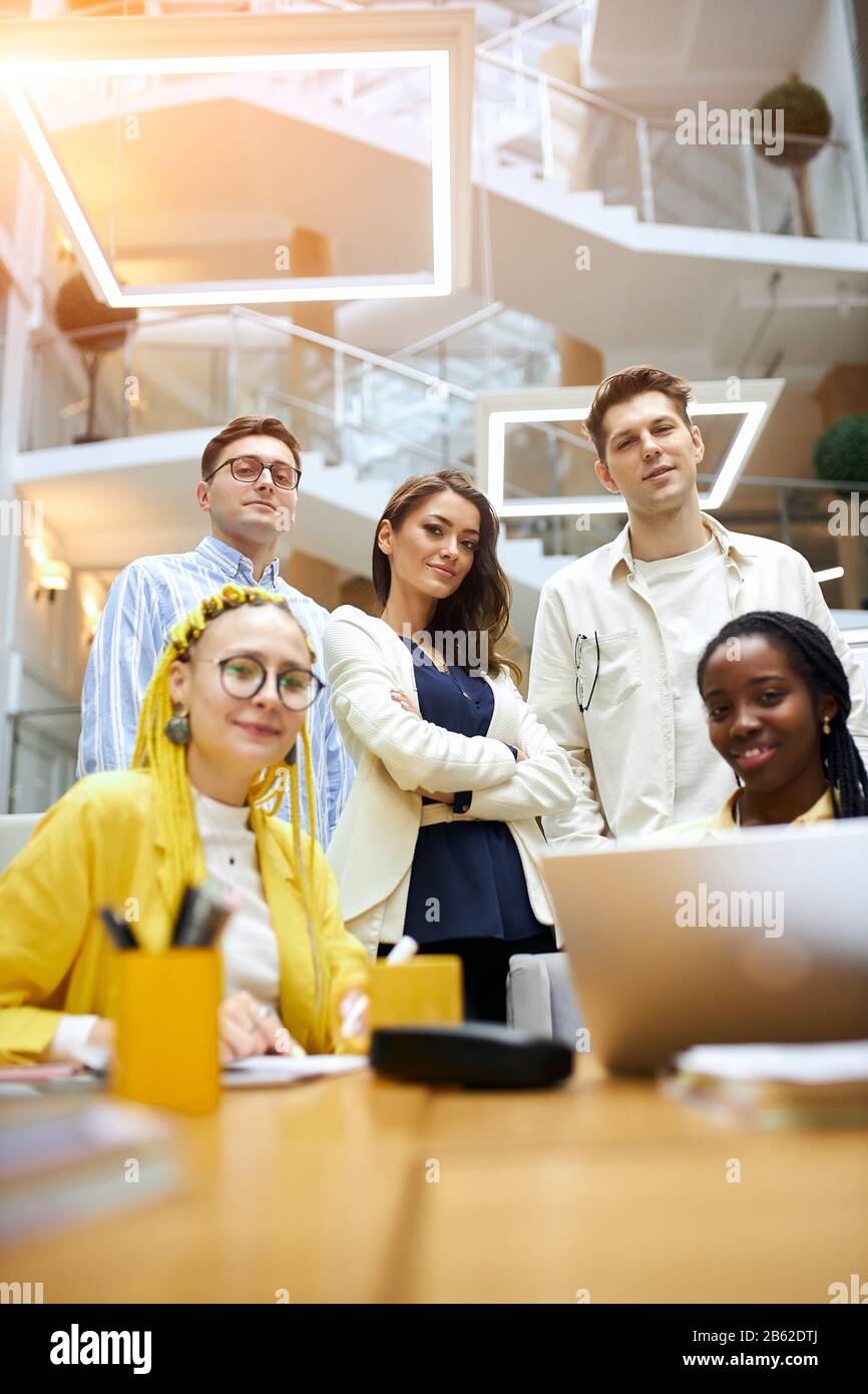 young active men and women working at office, vertical shot. female boss in fashion suit standing with crossed arms with her best helpers Stock Photo