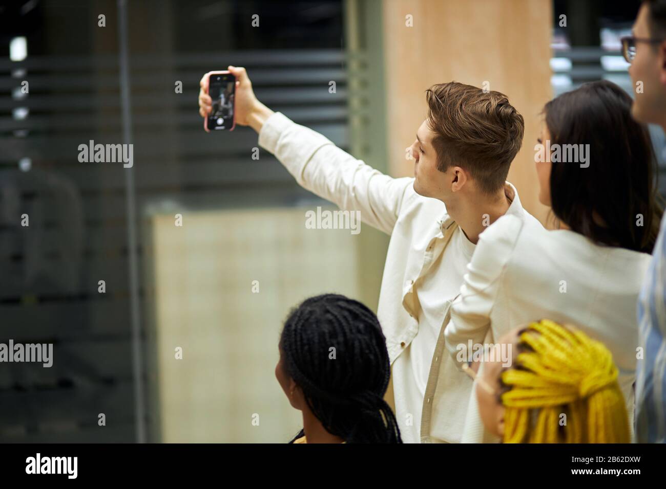 handsome blonde guy holding his mpbile phone, taking selfiew with his colleagues, close up photo. man testing his new camera, smart phone, checking th Stock Photo
