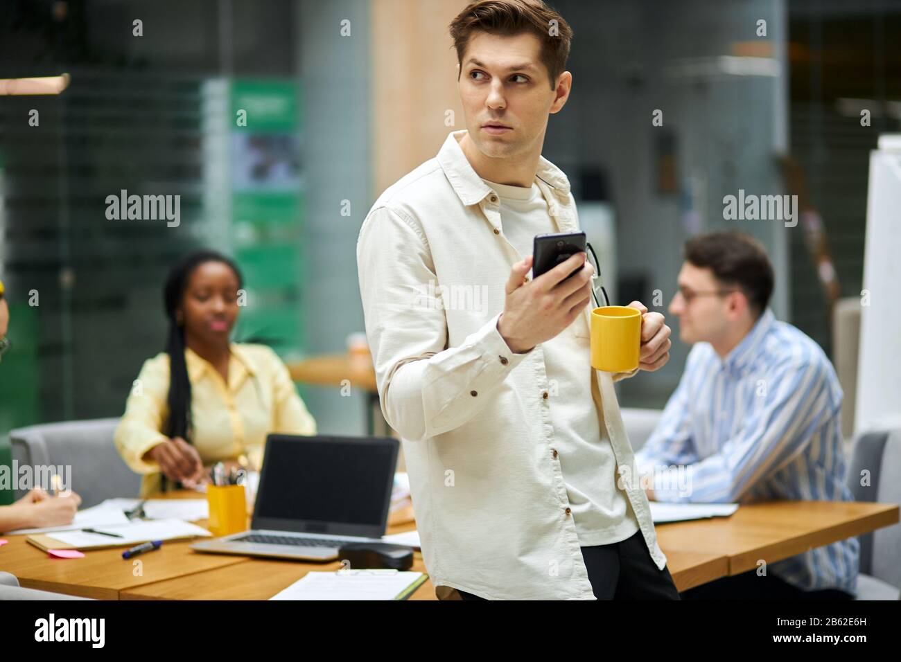 handsome serious man holding smart phone, cup of tea, going to make a phone call, blurred background, free time, spare time, lifestyle Stock Photo
