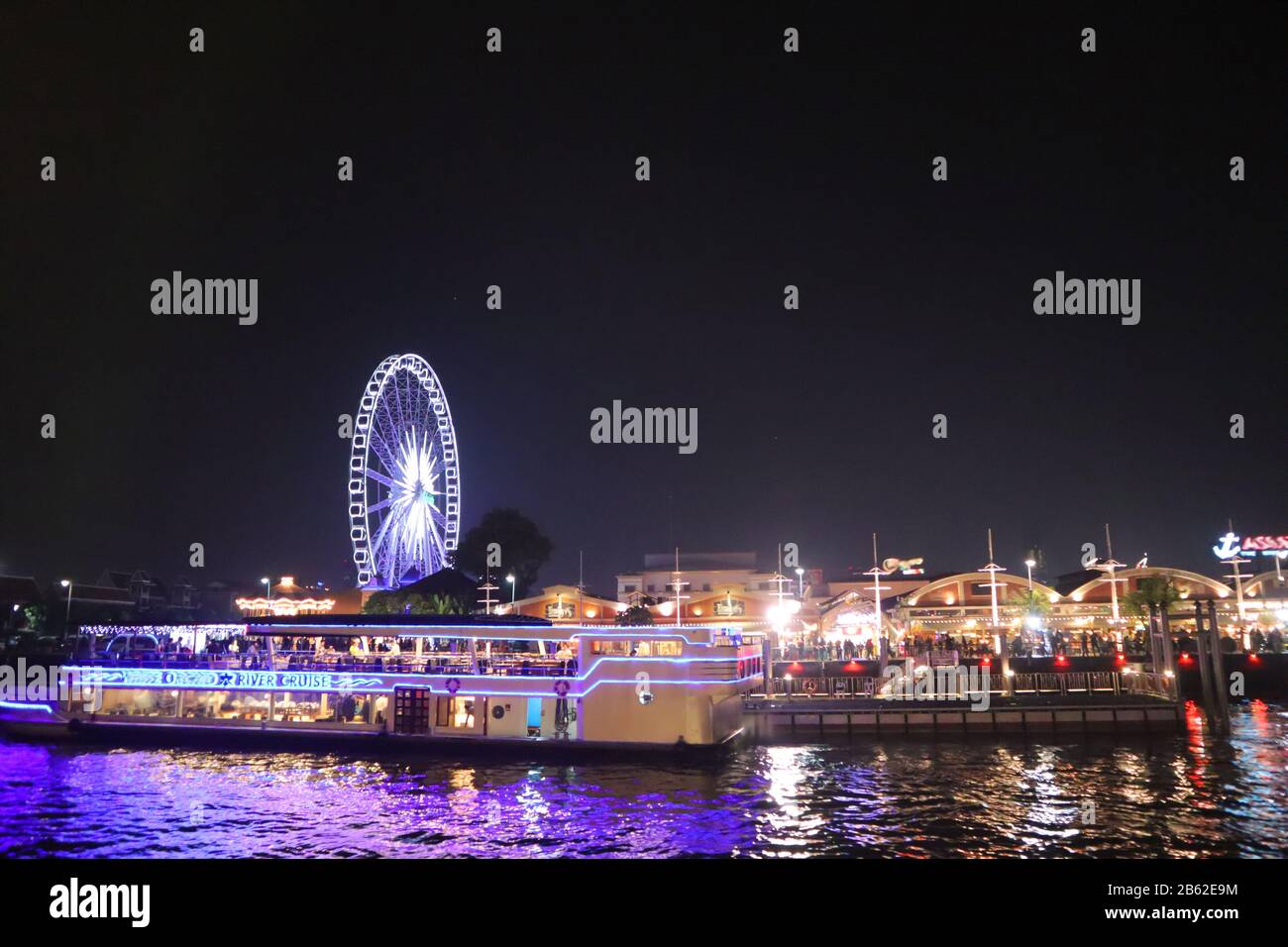 A trip boat at the embankment at Chao Phraya River in Bangkok city. cityscape in the evening. Nigt life in asia Stock Photo