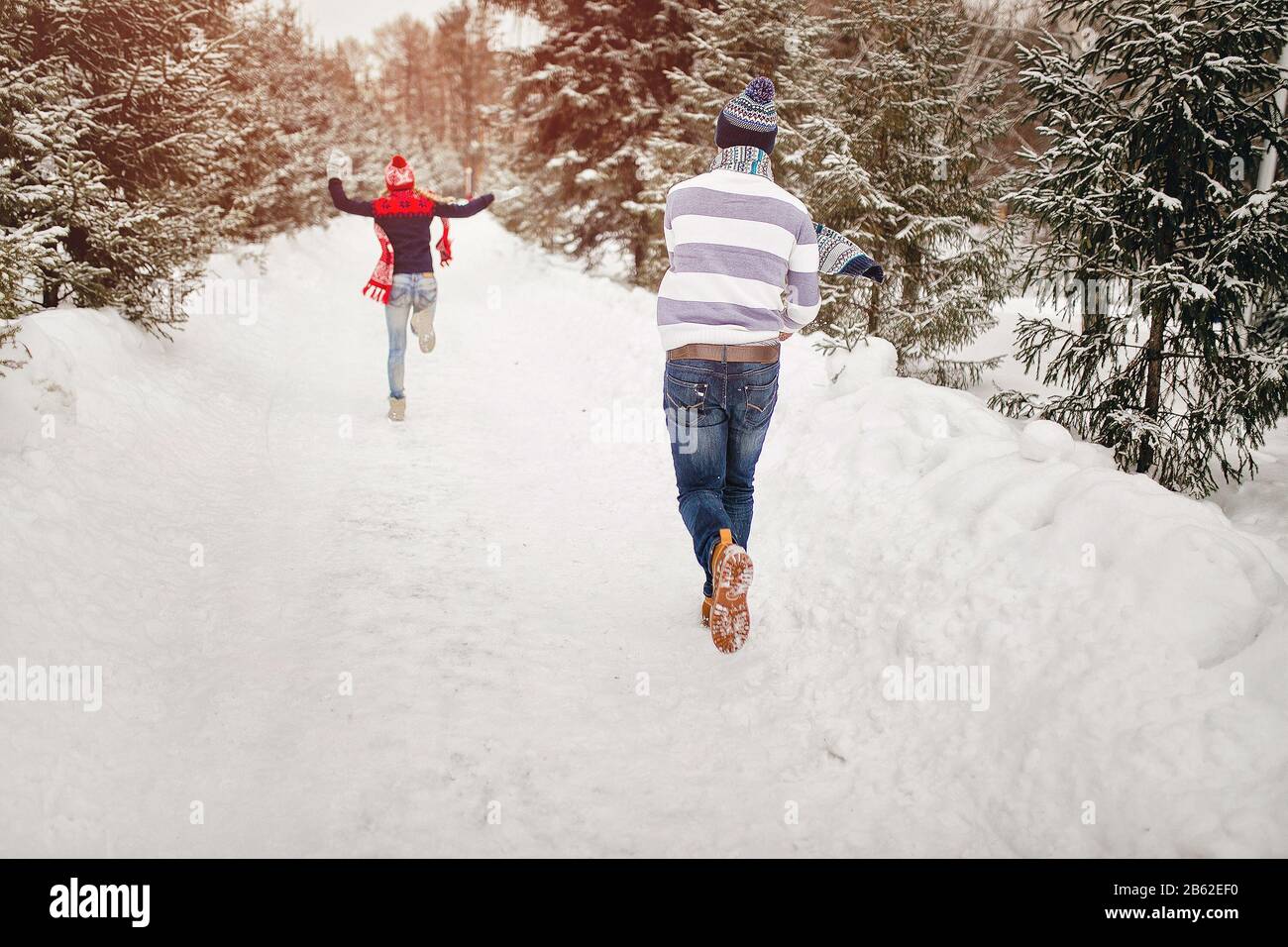 Snowball fight. Winter loving couple having fun playing catch up outdoors. Young joyful happy couple in love Stock Photo