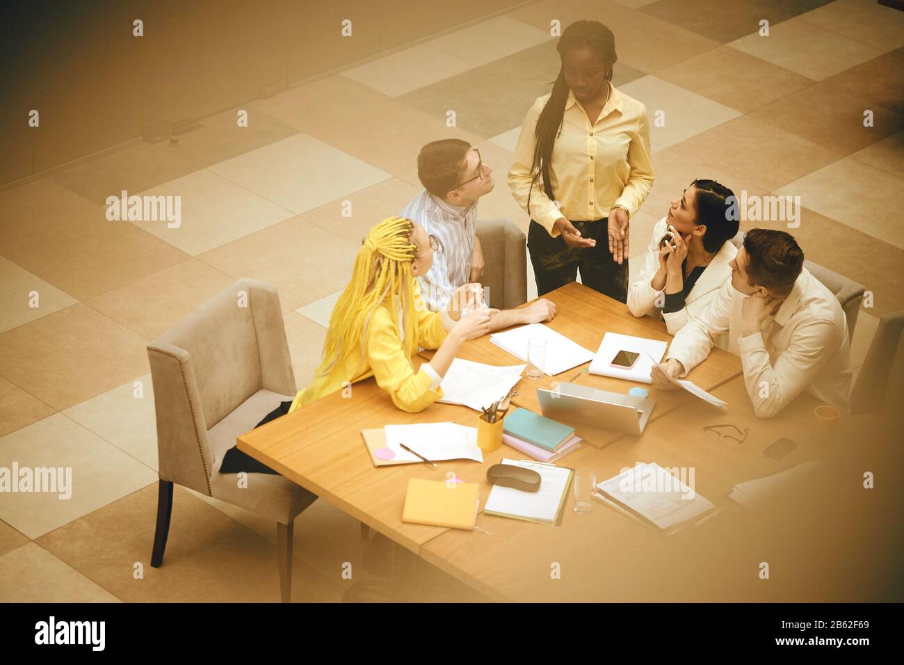 afro woman telling her colleagues that they are having financial burden, blurred photo. top view . serious conversation, failure, bad luck in the firm Stock Photo