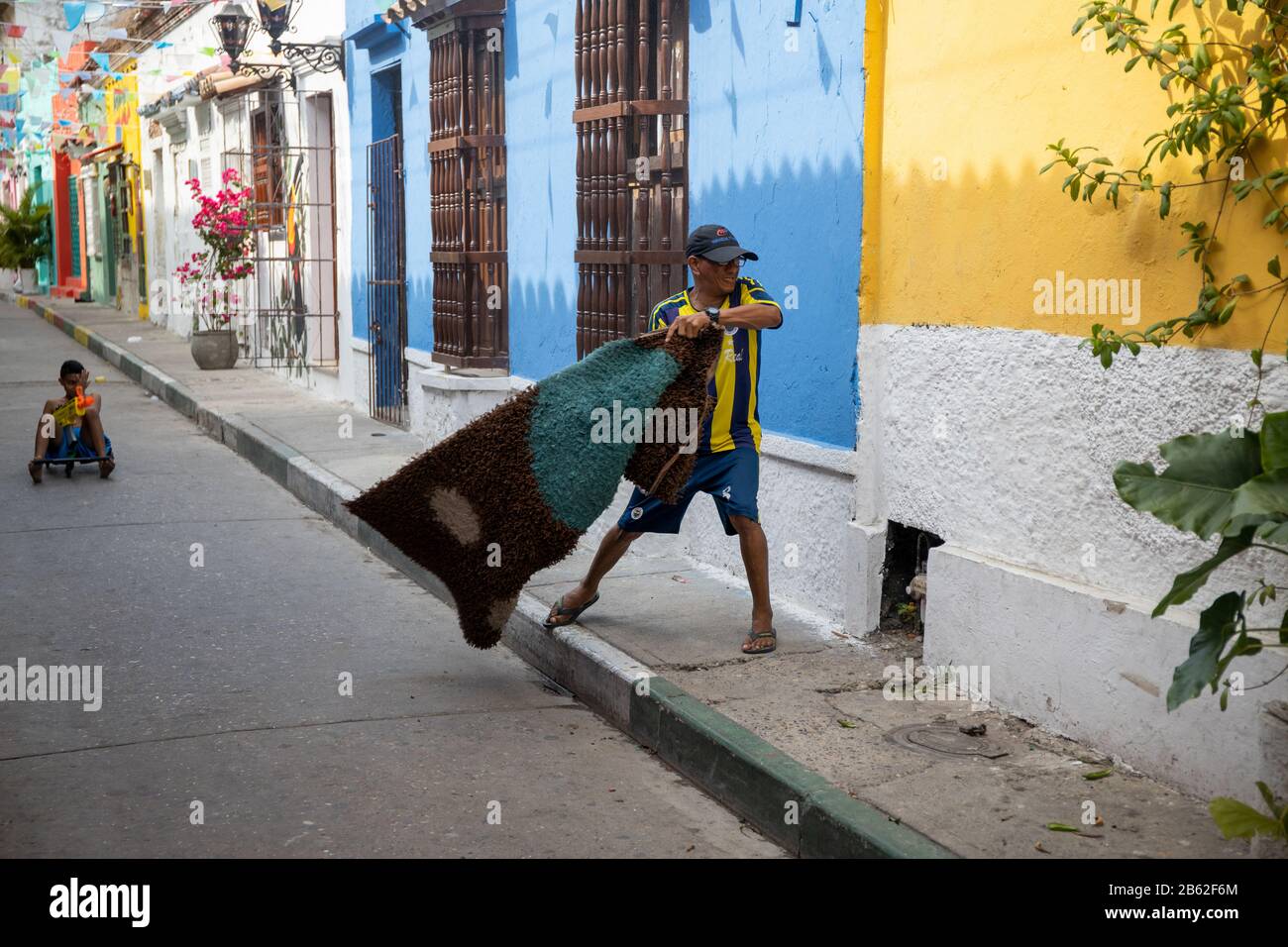 Life goes on in this busy tourist area in Getsemani, man cleaning the dust from a rug. Stock Photo