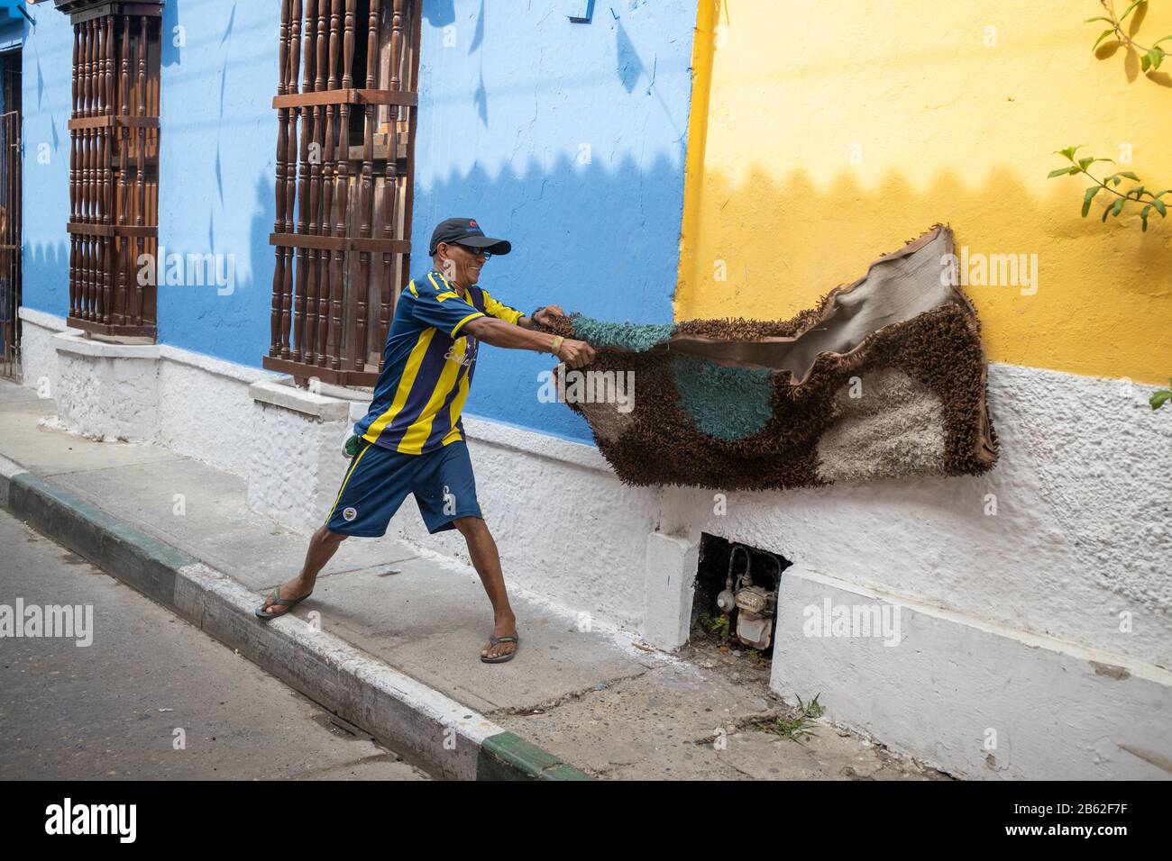 Life goes on in this busy tourist area in Getsemani, man cleaning the dust from a rug. Stock Photo
