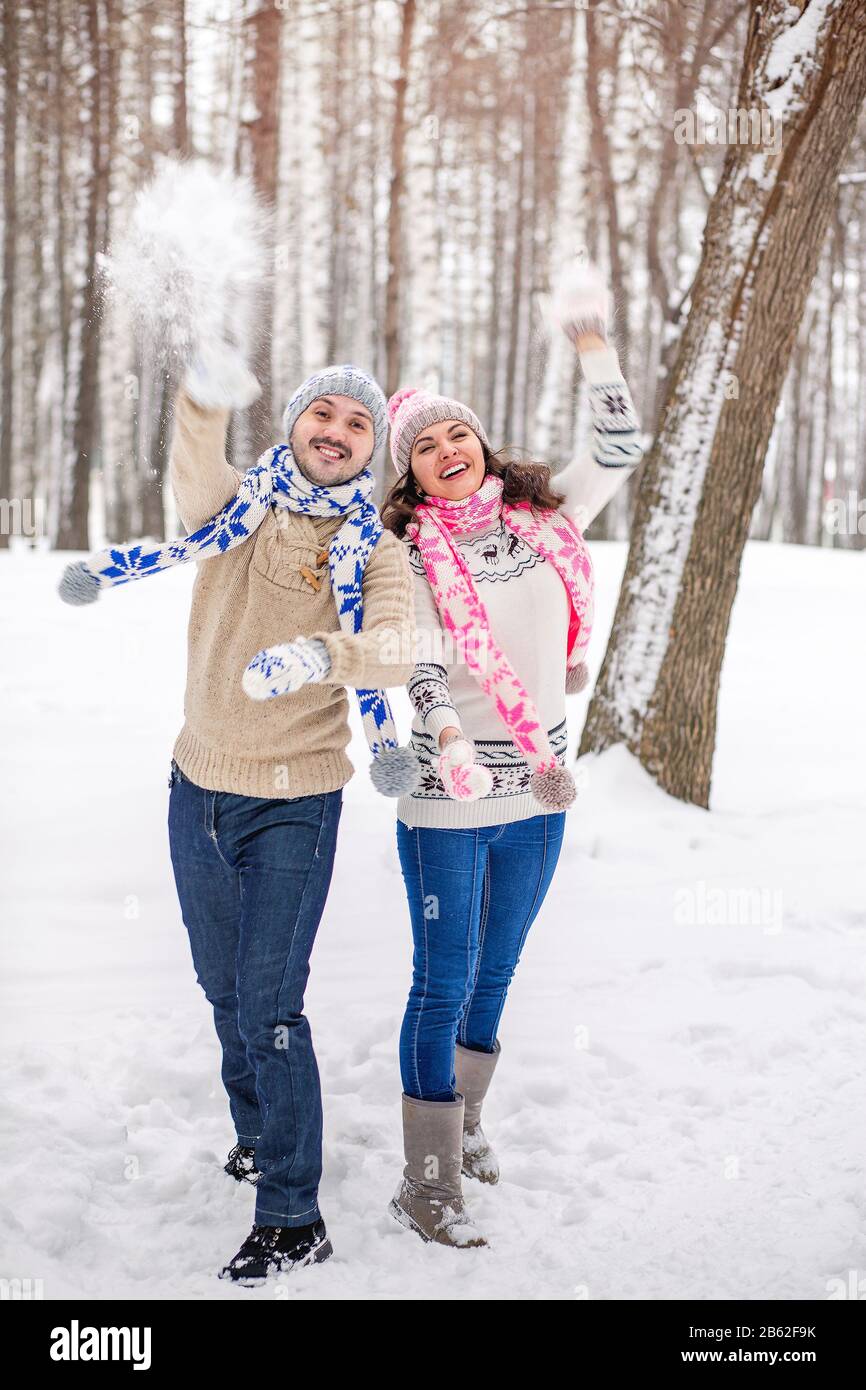 Snowball fight. Winter couple having fun playing in snow outdoors. Young joyful couple in love Stock Photo
