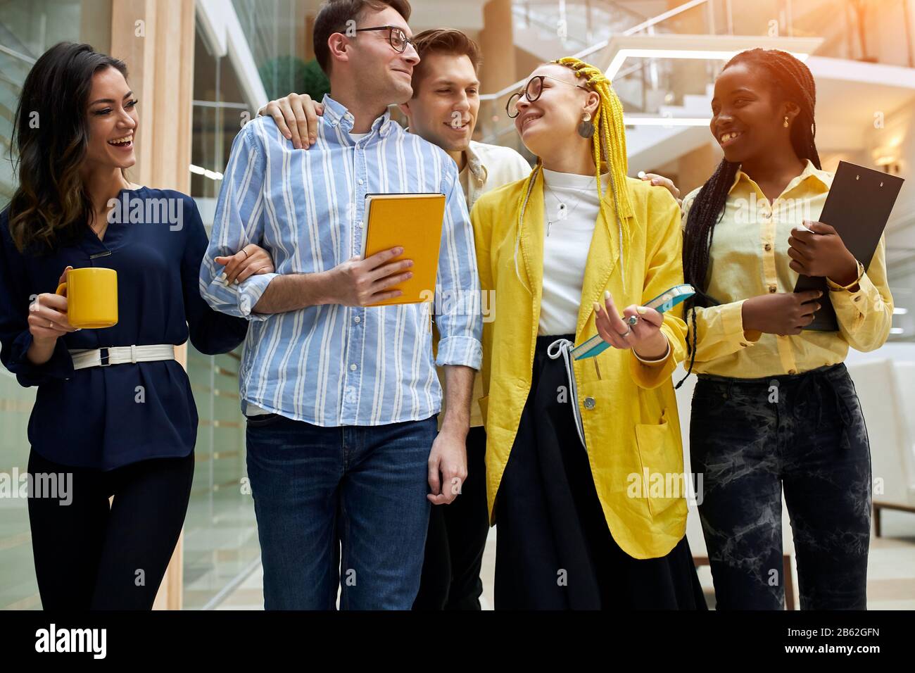 funny young people having fun in the office, telling jokes while walking, young poeple going to have lunch. Stock Photo