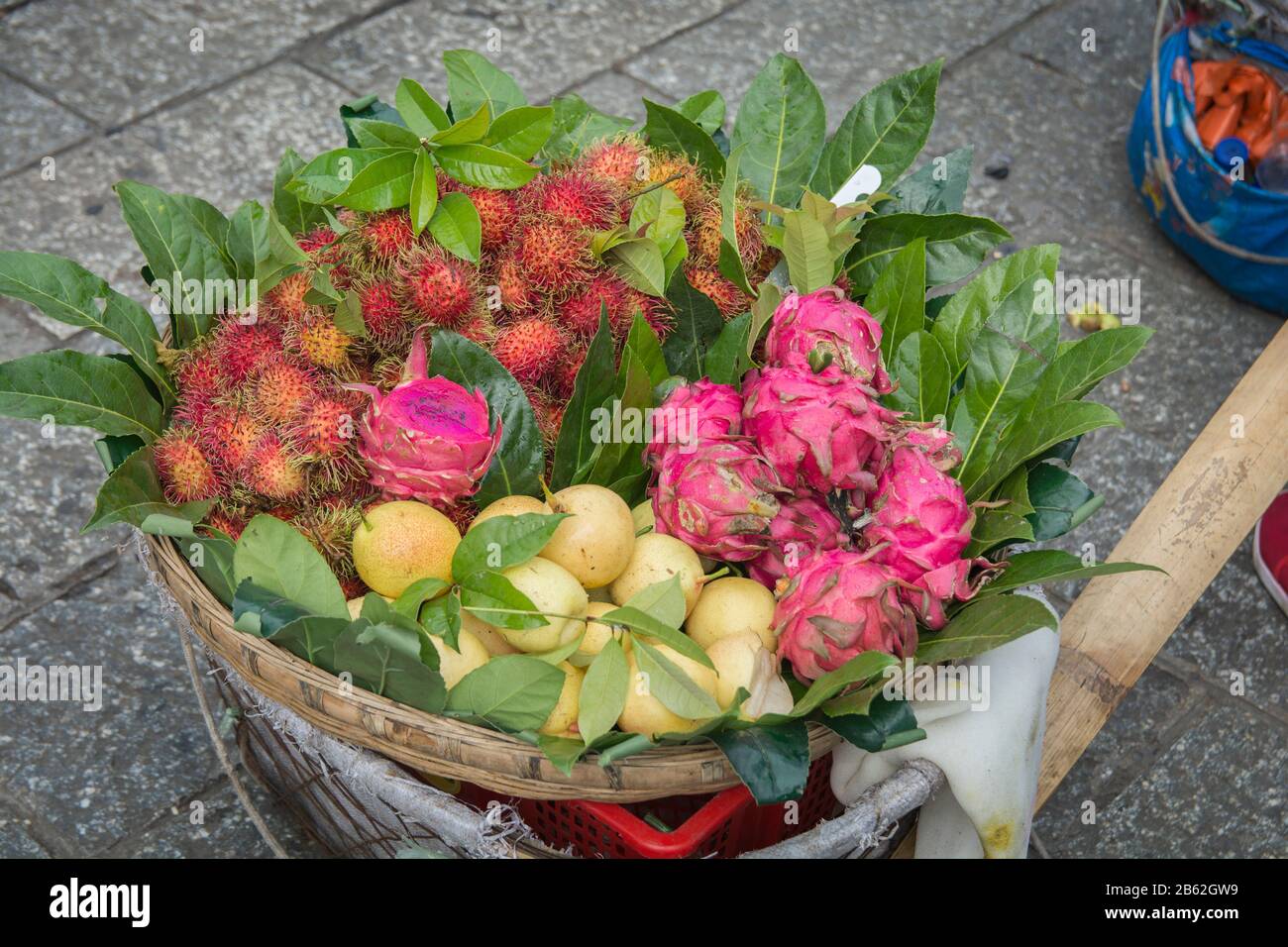 Colorful exotic fruits basket, containing Dragon fruits, Rambutan and pears, being sold in the market of Dali, Yunnan, China Stock Photo