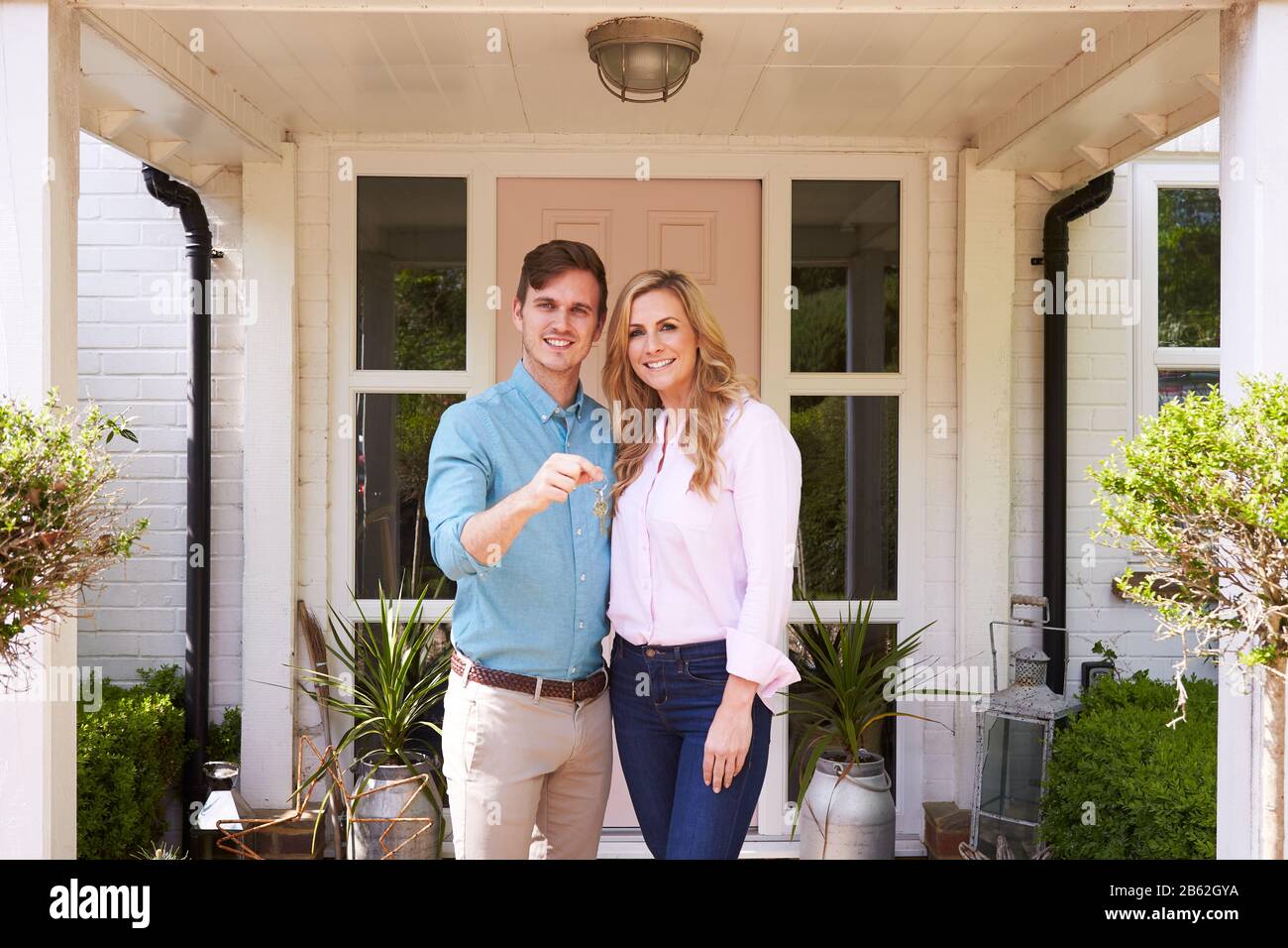 Portrait Of Couple Holding Keys To New Home Standing Outside Front Door ...