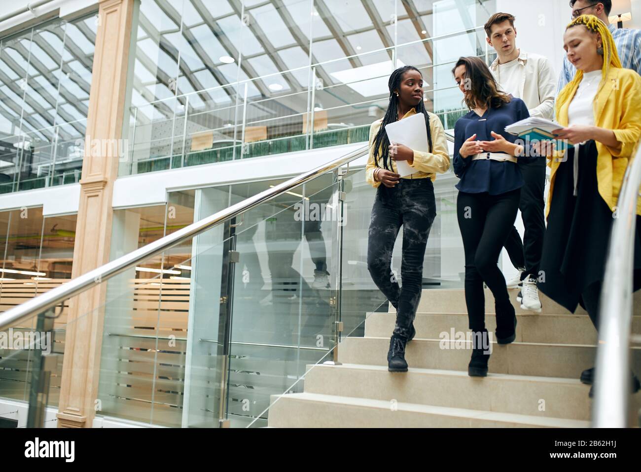 young ambitious talented office workers talking, discussing a new project, copy space, students walking in the building, a group of young people going Stock Photo