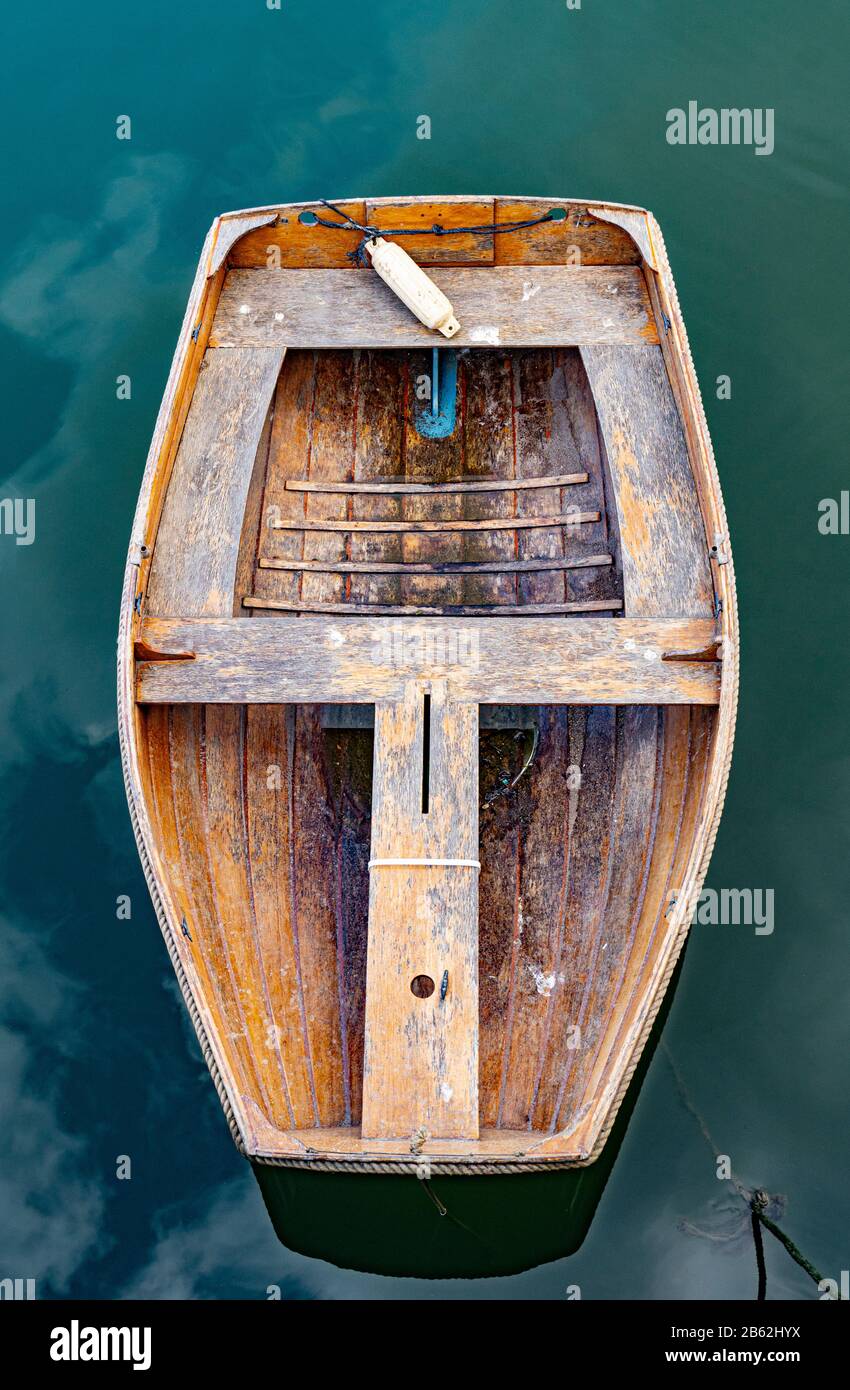Overhead view of a small empty old wooden rowing boat floating in the water at West Bay near Bridport in Dorset England UK Stock Photo