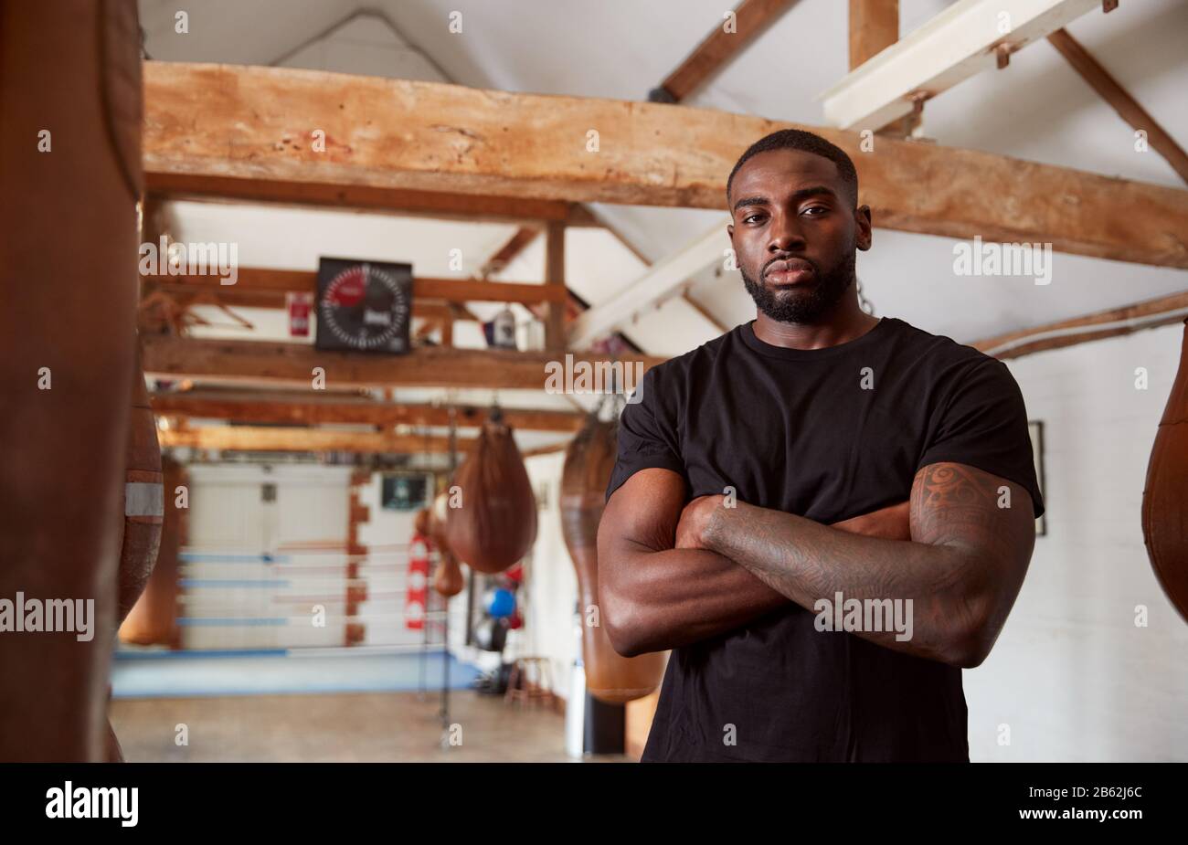 Portrait Of Male Boxer In Gym Standing By Old Fashioned Leather Punch