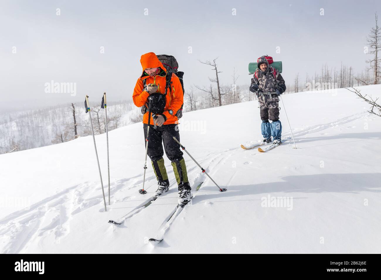 High altitude view of two skiers walking on a mountain ridge in the Ural mountains. One hiker looking in navigator map Stock Photo