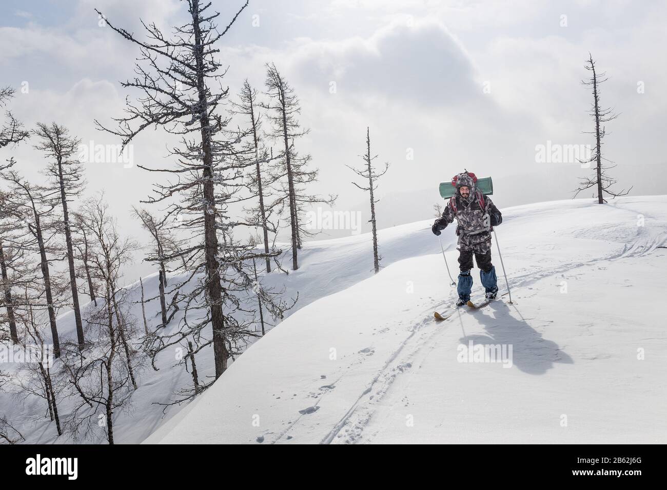 Male skier hiking with a backpack in winter mountains and forest Stock Photo