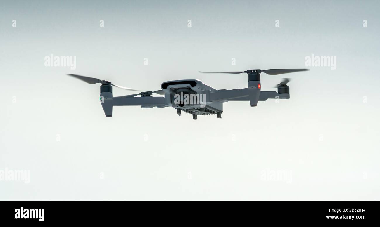 A quadrocopter drone with camera hangs in the air against a blue sky. Shooting photos and videos from the air at altitude. Modern technologies of unma Stock Photo