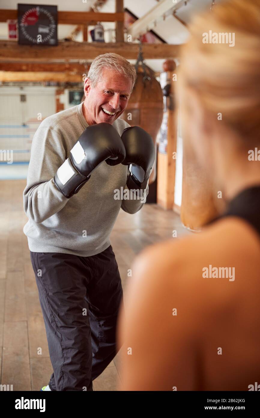 Senior Male Boxer Sparring With Younger Female Coach In Gym Using ...