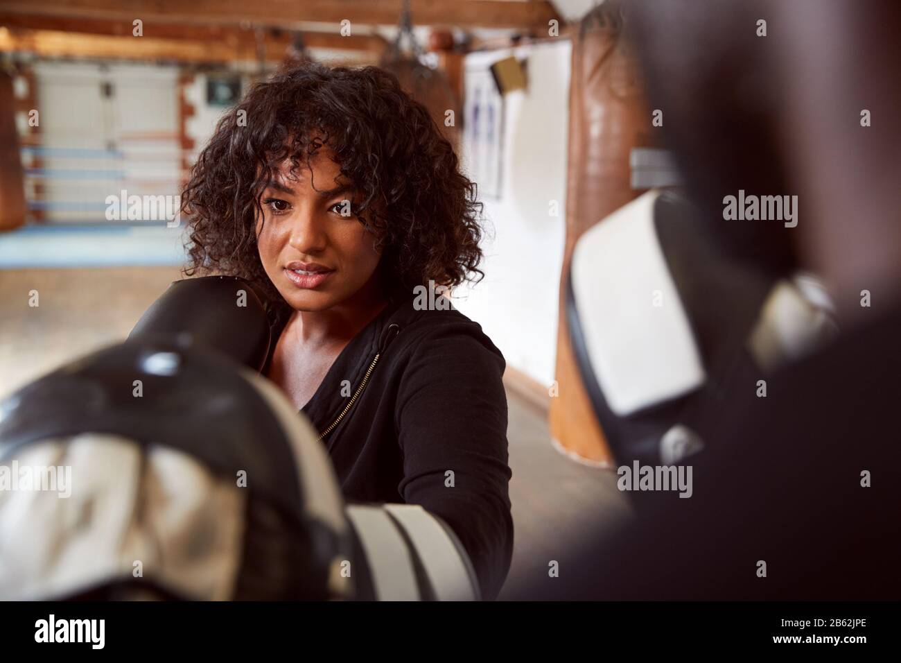 Male Personal Trainer Sparring With Female Boxer In Gym Using Training Gloves Stock Photo