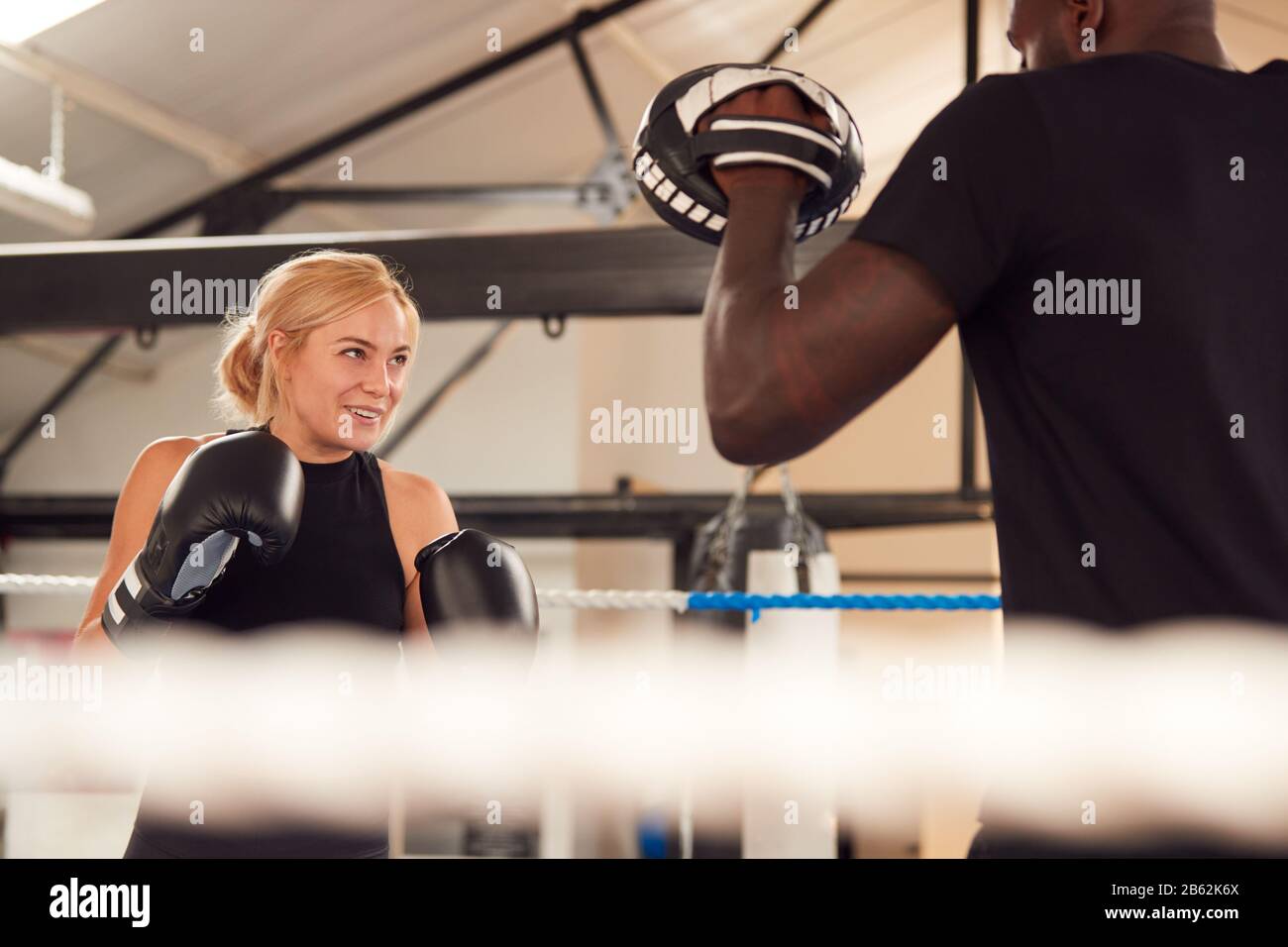 Male Personal Trainer Sparring With Female Boxer In Gym Using Training ...