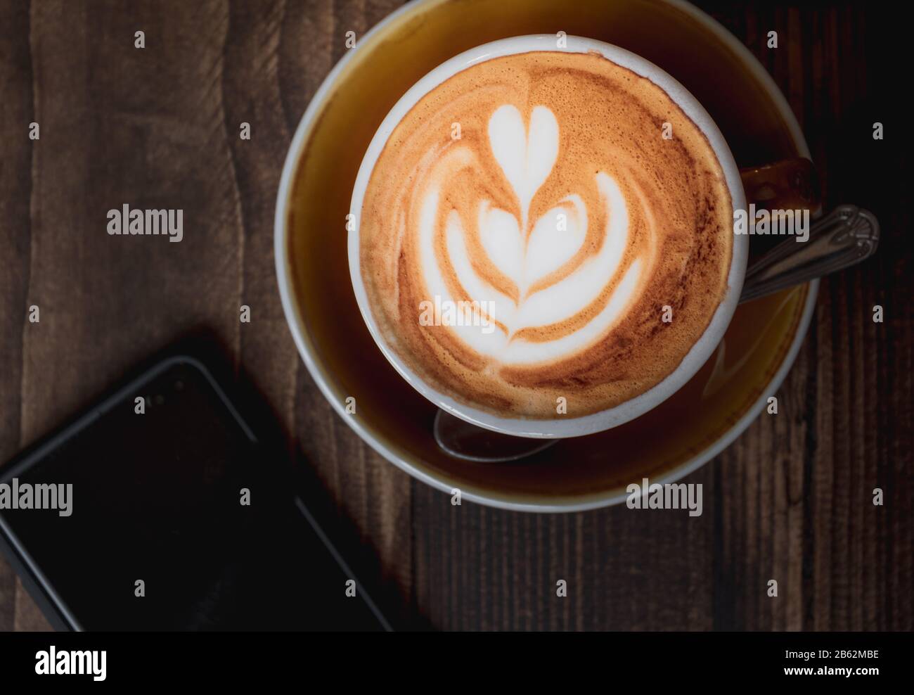 Top down image of a Latte and mobile phone showing the coffee culture or weekend lifestyle of millennials Stock Photo