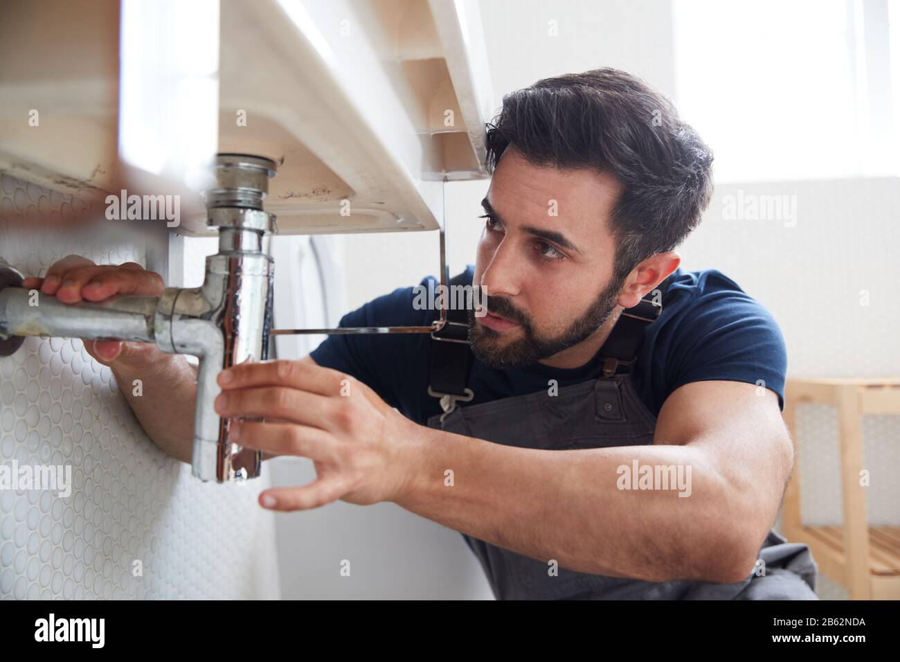 Male Plumber Working To Fix Leaking Sink In Home Bathroom Stock Photo Alamy