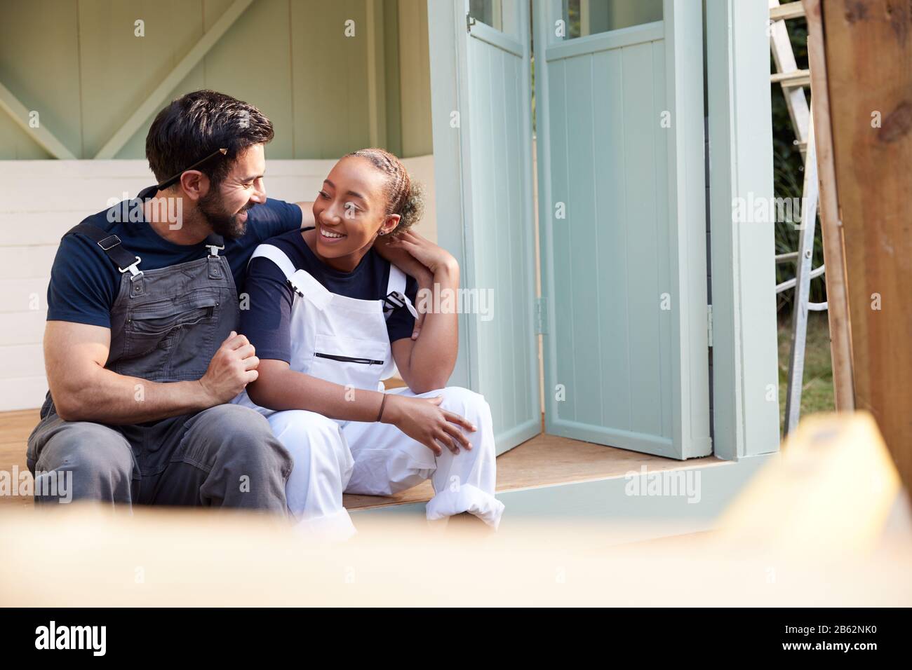 Couple Taking A Break From Building Outdoor Summerhouse In Garden Stock Photo