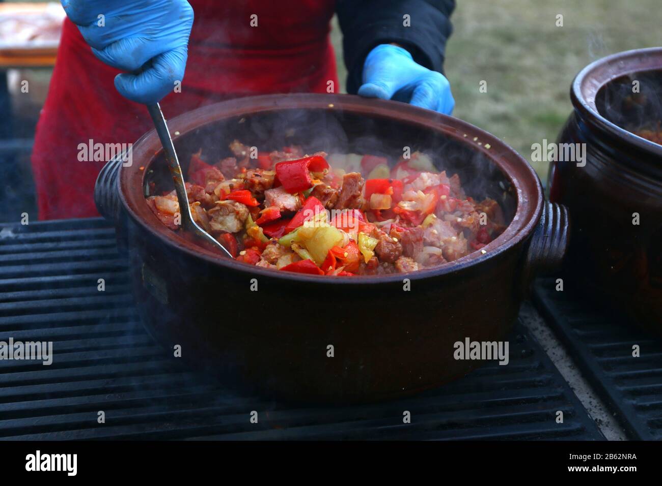 Traditional Serbian Leskovacka Muckalica - a spicy stew of pork, tomatoes and peppers prepared in a clay pot Stock Photo