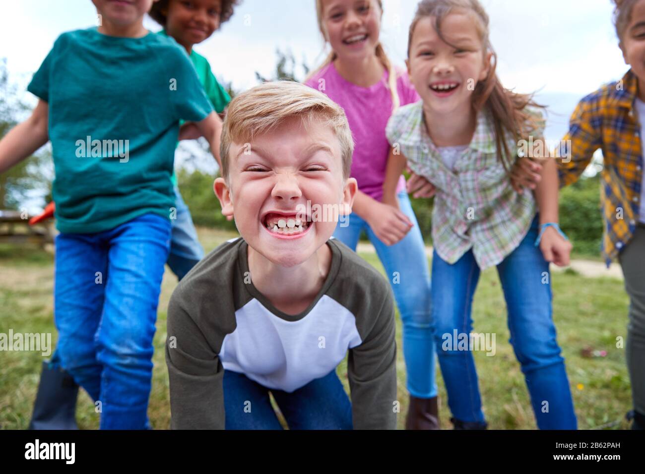 Portrait Of Children On Outdoor Activity Camping Trip Pulling Faces Having Fun Playing Game Together Stock Photo