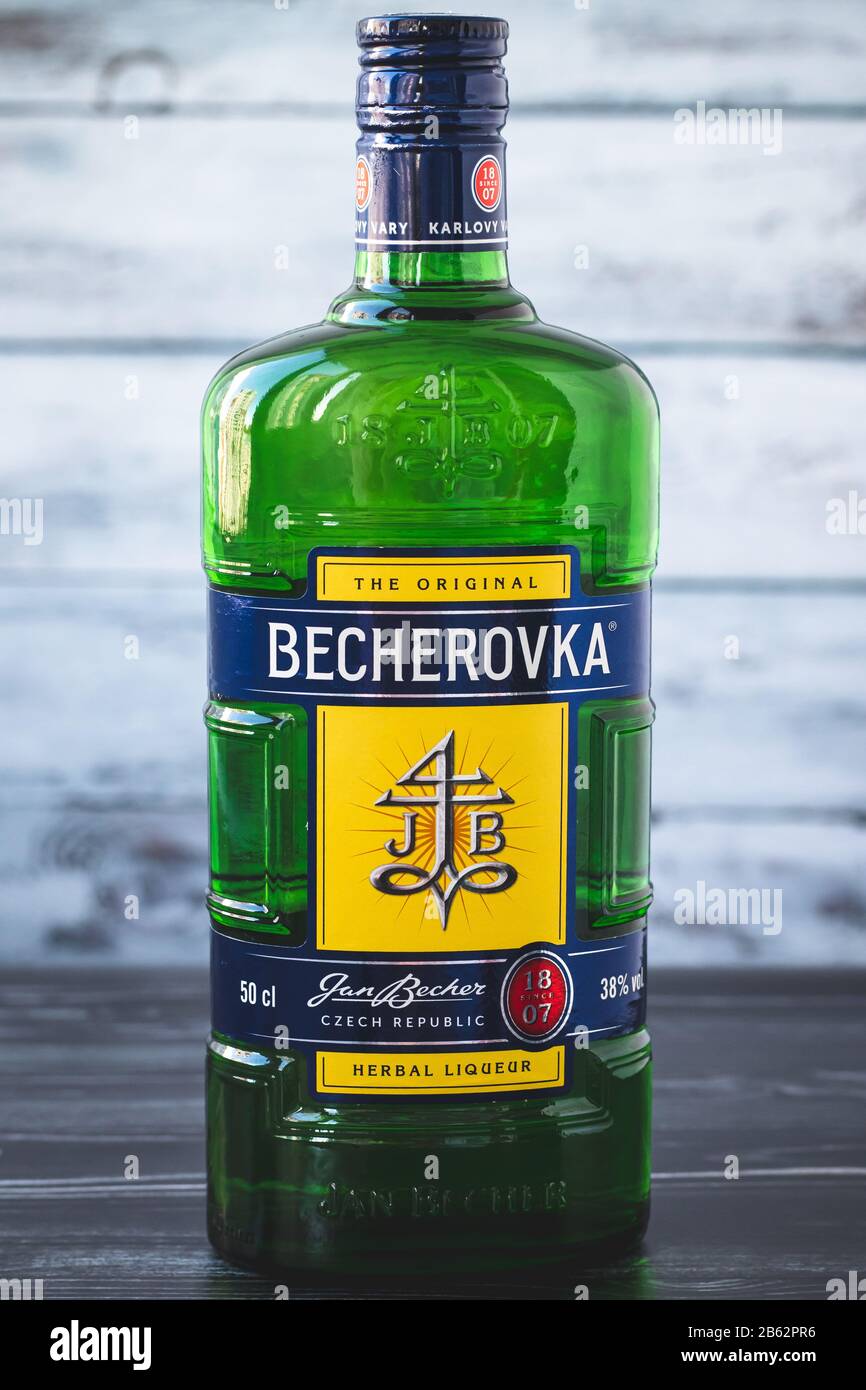 Kharkiv, Ukraine, November 15, 2019: A full glass green bottle of becherovka on gray wooden background. Strong drink - czech herbal liqueur. Illustrat Stock Photo