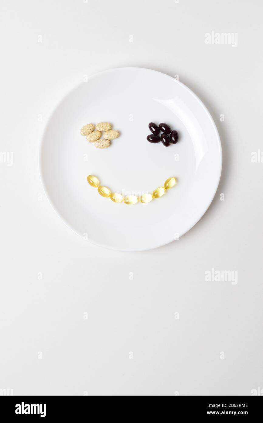 Astaxanthin, multivitamins and fish oil in a shape of smile on a white