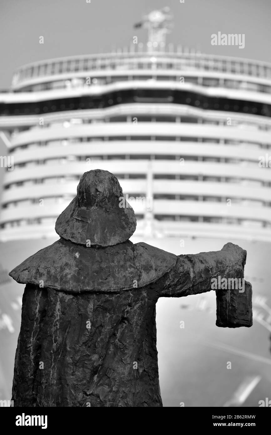bronze statue of the sailor and behind large cruise ship savona italy Stock Photo