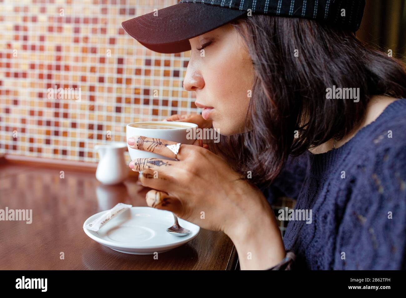 the girl drinks coffee at a roadside cafe. Warm Colors Toned Stock