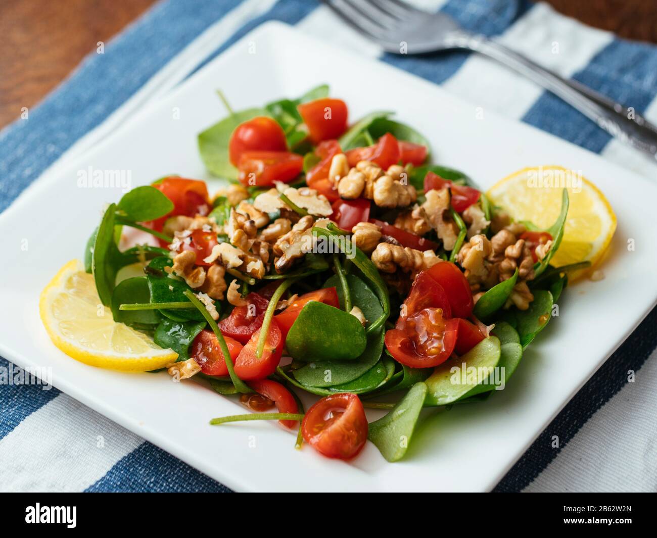 Winter purslane salad with tomatoes and toasted walnuts. Stock Photo