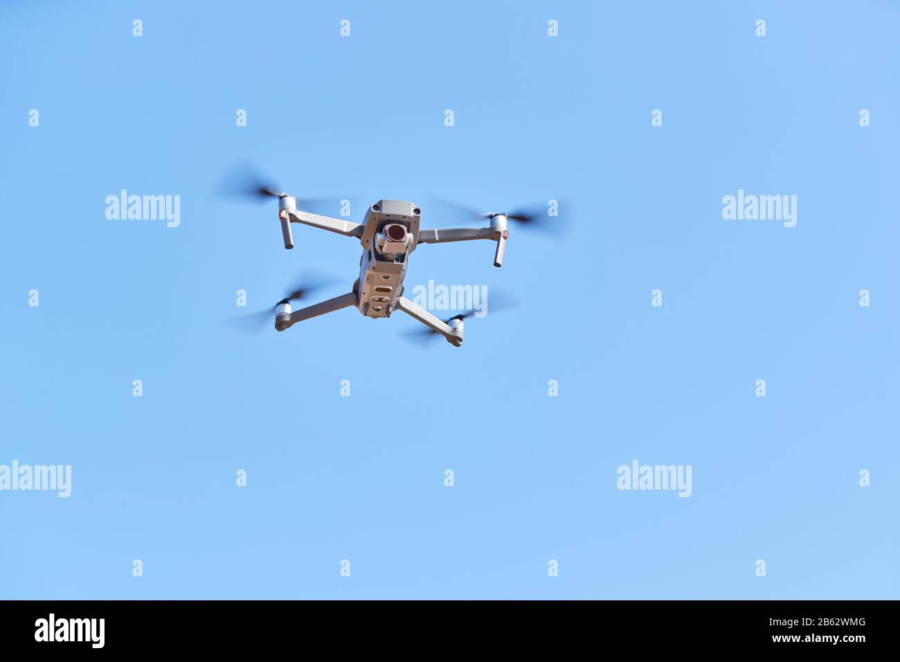 Drone With Camera Flying Against Clear Blue Sky Stock Photo