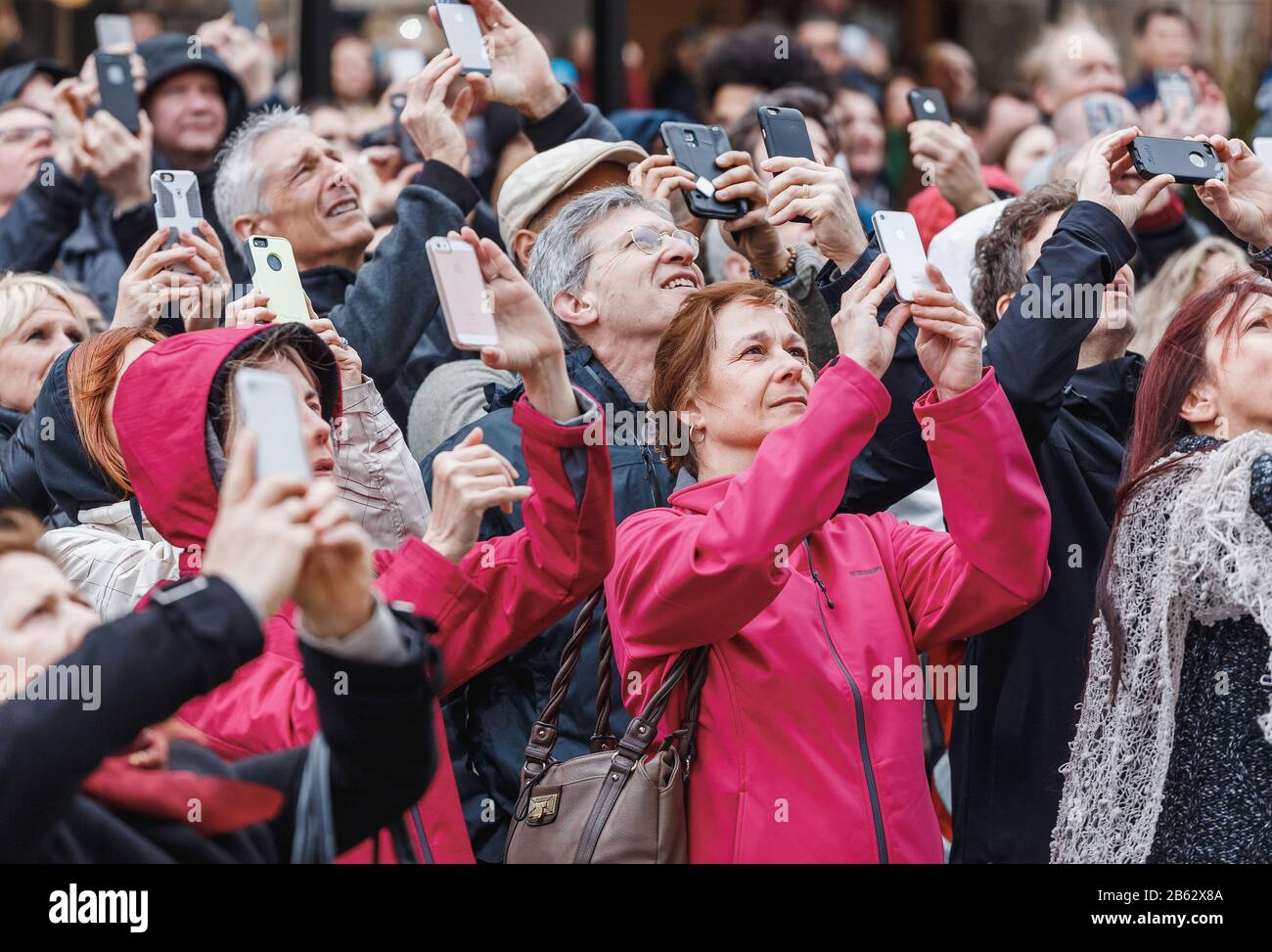 PRAGUE, CZECH REPUBLIC - 18 MARCH, 2017: A multinational large crowd of tourists photograph on smartphones and look up at the city's landmark Stock Photo