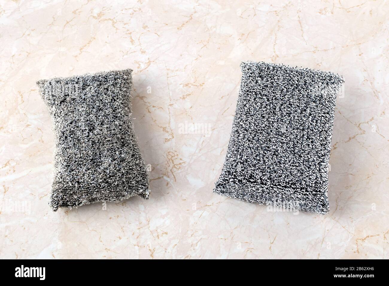 Old and new silver foam sponges for dishwashing on a kithen table