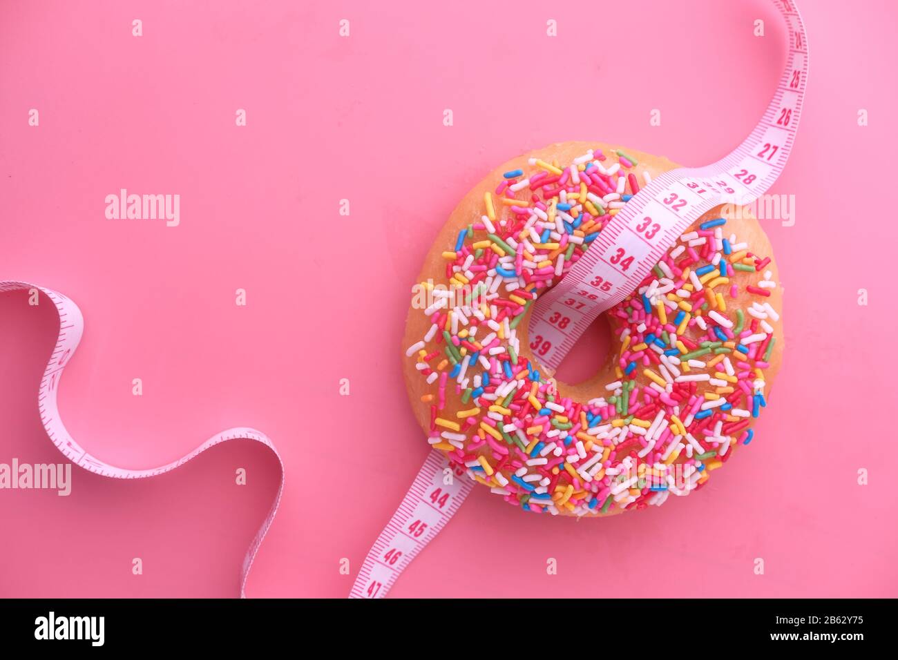 Close up of donuts and measurement tape on pink background Stock Photo