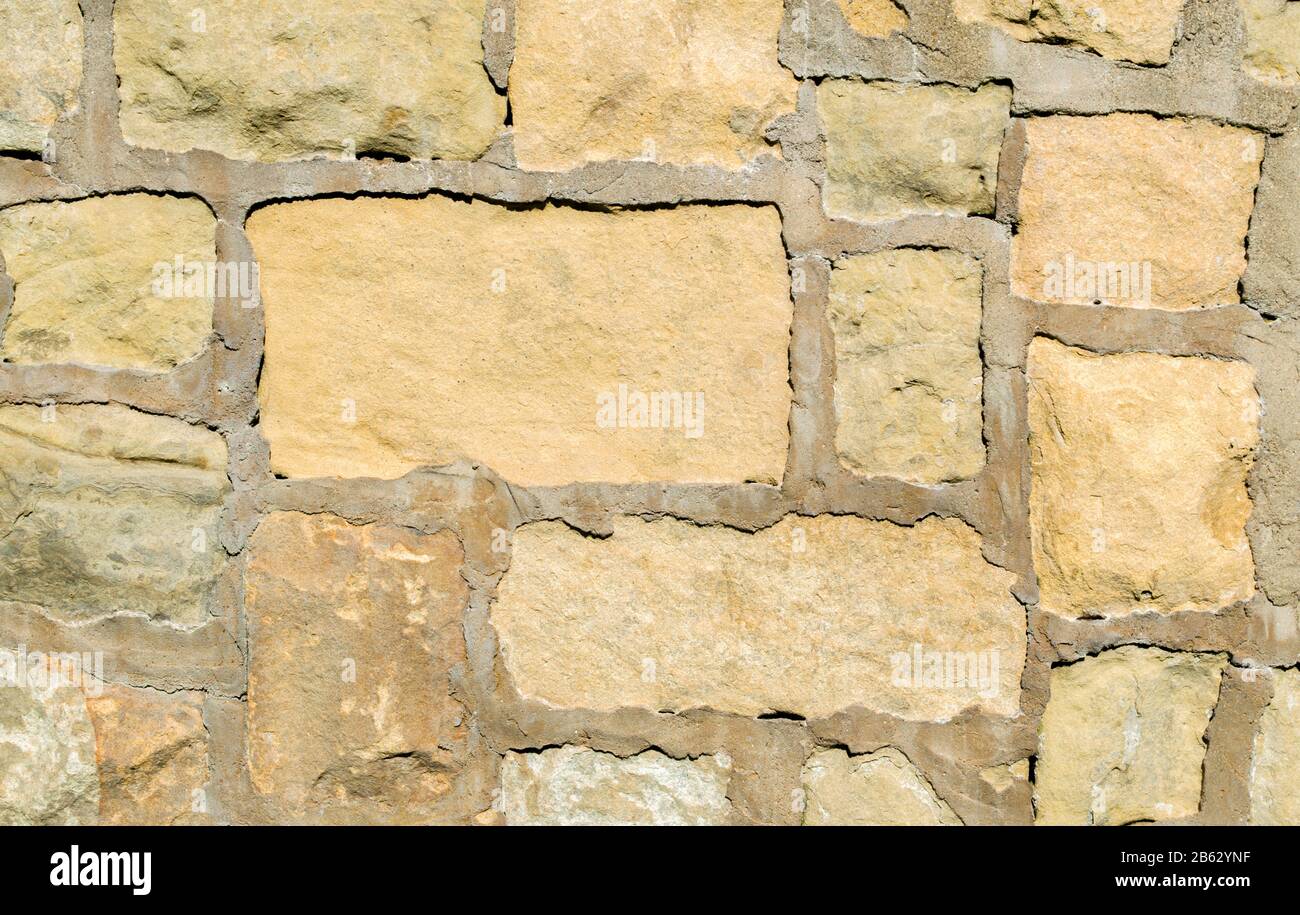 background texture-close up of vintage pastel sandstone block wall with grout Stock Photo